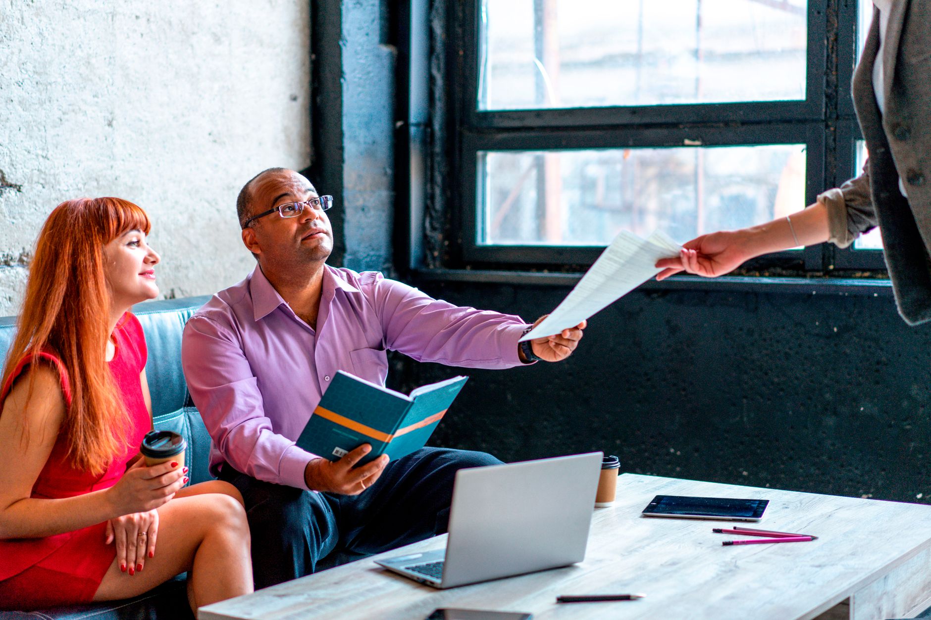 A group of professionals working together in a modern office setting, exchanging documents and ideas.